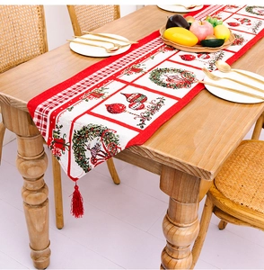 Detailaufnahme des Weihnachts-Tischläufers mit Kranzmuster und roten Quasten auf Holz