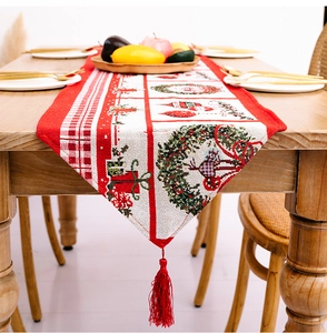 Detail eines roten Weihnachts-Tischläufers mit festlichen Kränzen und dekorativen Quasten
