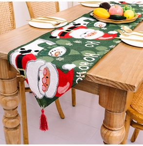 Detail der Textur des grünen Weihnachts-Tischläufers mit Weihnachtsmann und roten Quasten
