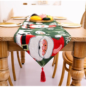 Detailaufnahme des grünen Weihnachts-Tischläufers mit Schneemann-Jacquard und roten Quasten