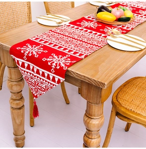 Nahaufnahme eines festlichen roten Weihnachtstischläufers mit Schneeflocken und Quasten