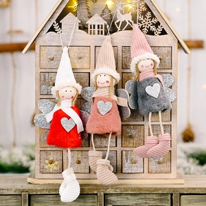Three plush Christmas angel ornaments with sequin wings and hearts on a wooden background