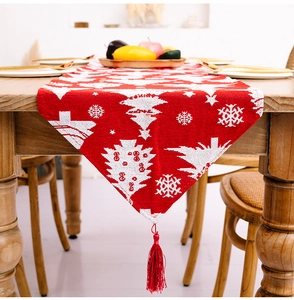 Detail eines roten Weihnachts-Tischläufers mit weißen Schneeflocken, Bäumen und Quasten