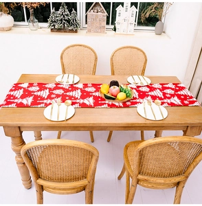 Detail eines roten Weihnachts-Tischläufers mit weißen Baummustern auf rustikalem Holztisch