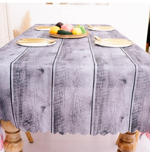 Detail of dark grey wood grain tablecloth featuring decorative scalloped edges on a table