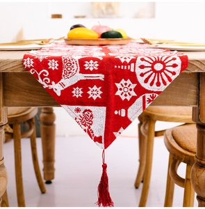 Detailansicht von Weihnachts-Tischläufer mit Rentier-Motiv und roter Quaste auf Holztisch