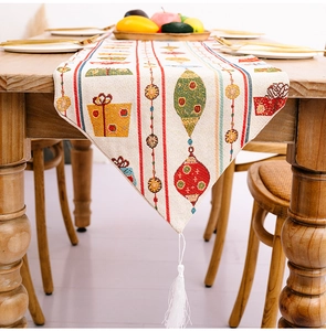 Detail eines Weihnachts-Tischläufers mit festlichen Drucken und weißen Quasten am Ende