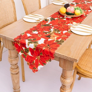 Christmas table runner with red poinsettia floral prints on wooden dining table