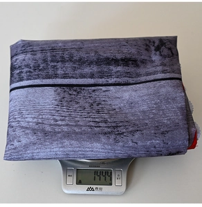 Close-up of a folded grey wood grain tablecloth being weighed on an electronic scale