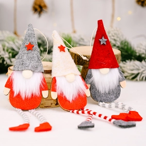 Three-piece Christmas gnome ornaments with hanging legs and stars on snow-covered pine branches