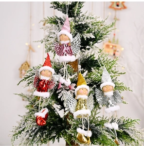 Detail of sequined angel ornaments with wings hanging on a snowy Christmas tree