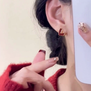 Boucles d'oreilles cœur rouge avec bord doré portées par un mannequin au style doux