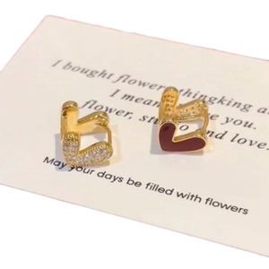 Boucles d'oreilles huggies dorées avec cœur en émail rouge et zircons sur carte de support