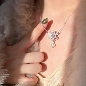Elegant snowflake pendant necklace with zircon stones and pearl on a winter sweater