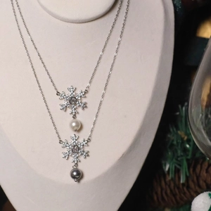 Silver snowflake zircon necklace with pearls on a festive winter-themed display stand