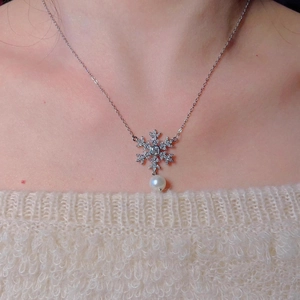 Elegant snowflake pearl necklace with zircon accents worn on a beige knit sweater