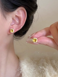 Detailed view of yellow square crystal stud earrings with a sparkling zircon halo