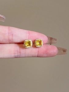 Macro detail of cushion-cut yellow gemstone earrings with a halo of white diamonds