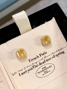 Macro shot of square yellow gemstone stud earrings with a halo of small diamonds