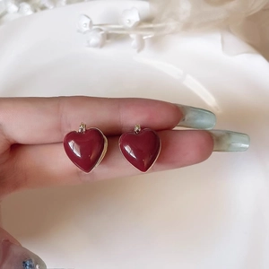 Détail des boucles d'oreilles cœur vintage bordeaux avec bordure dorée élégante