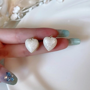 Détail macro de boucles d'oreilles cœur en émail français avec texture marbre blanc et or