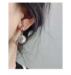 Close-up of silver coin earrings featuring Elizabeth II relief on a female model