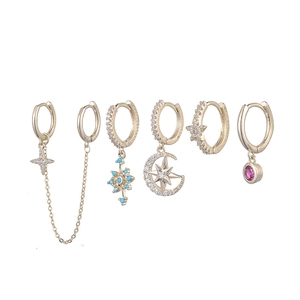 Detail of six gold earrings set featuring star, moon, and blue snowflake pendants