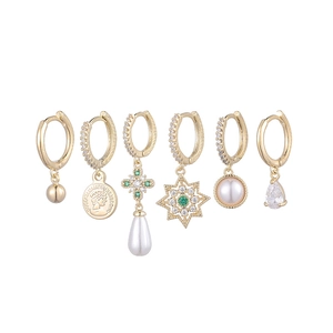 Set of six gold drop earrings with pearls, coins, and star pendants on white background