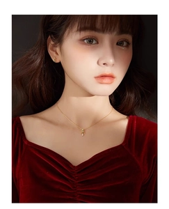 Détail du collier sapin de Noël doré et des créoles sur une chemise en velours rouge
