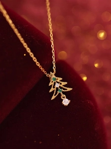 Macro d'un pendentif sapin de Noël doré avec cristaux verts sur velours rouge