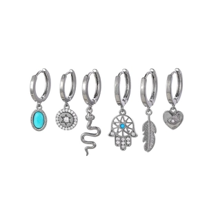 Detail of silver hoop earrings set with star, moon, turquoise and hamsa charms