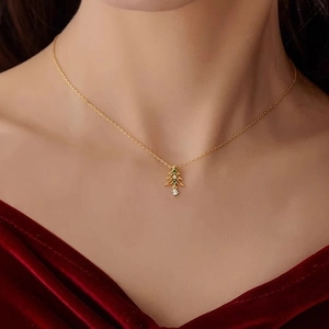 Collier pendentif sapin de Noël doré avec zircons verts et blancs sur fond de velours rouge