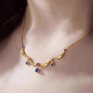 French vintage gold necklace with blue teardrop pendants and tassel design on model