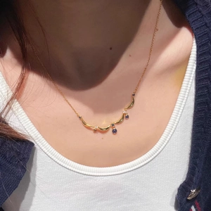 Close-up of a French vintage gold necklace with blue droplet stones on a female neck