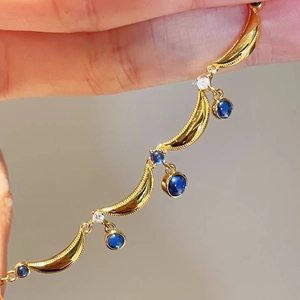 Macro detail of vintage gold chain with blue sapphire teardrops and intricate beadwork