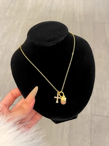 Detail of gold chain necklace with pink zircon egg pendant and crystal cross on neck model