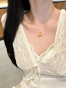 Close-up of gold necklace with heart lock pendant and pink zircon on female neck