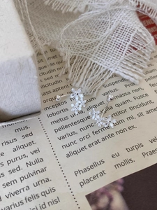 Detailed macro view of silver flower stud earrings on vintage book with lace decor