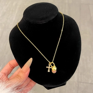 Gold pine cone necklace with pink zircon and cross pendant on a black bust model