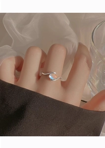 Close-up of minimalist silver wavy ring featuring an oval translucent moonstone on finger