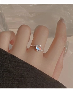 Detailed view of an open silver ring featuring a wave design and iridescent opal stone