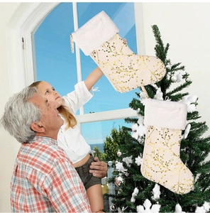 Detail of plush Christmas stocking with gold berry branch patterns and white faux fur trim