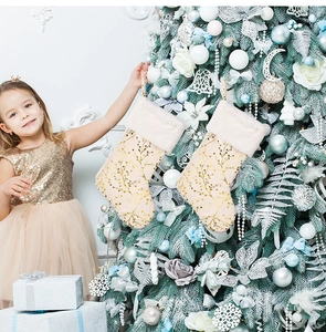 Detail of luxury champagne plush Christmas stockings with gold branch pattern by a tree