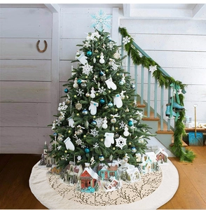 Detail of plush Christmas tree skirt with golden branch patterns and Nordic snow house decor