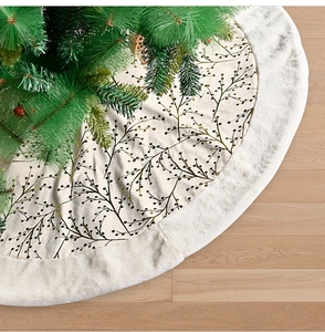 Detail of plush Christmas tree skirt with golden branch patterns on wood floor
