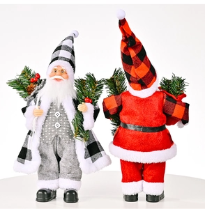 Detail von Weihnachtsmann-Figuren im Karomuster mit festlichen Tannenzweigen und Beeren