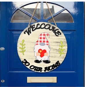 Close-up of wooden welcome gnome door sign with red heart and twine on dark blue door
