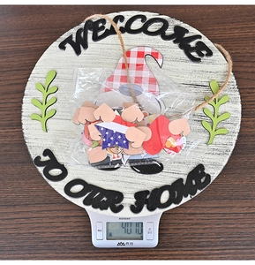 Close-up of wooden welcome sign weighing 401g on a scale with gnome and accessories