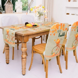 Detail of autumn table runner and chair covers with pumpkin bicycle and maple leaf motifs