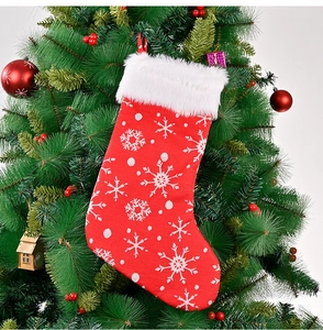Detail of red Christmas stocking with white faux fur cuff hanging on a festive tree branch